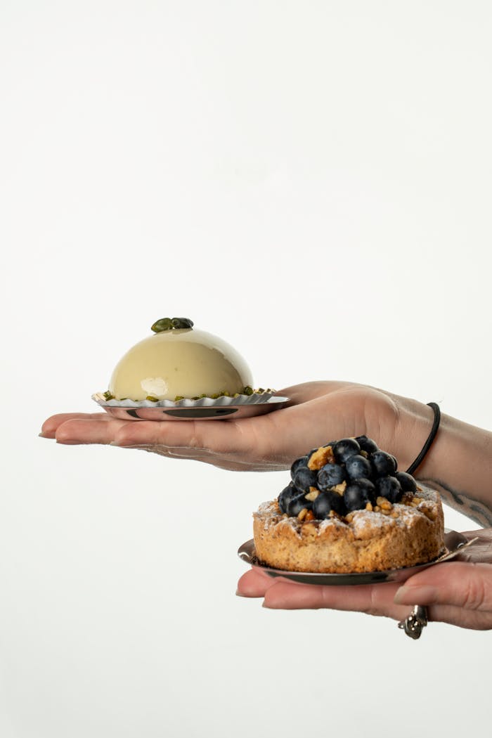 Studio shot of fine French pastries on hands, showcasing elegant dessert presentation.